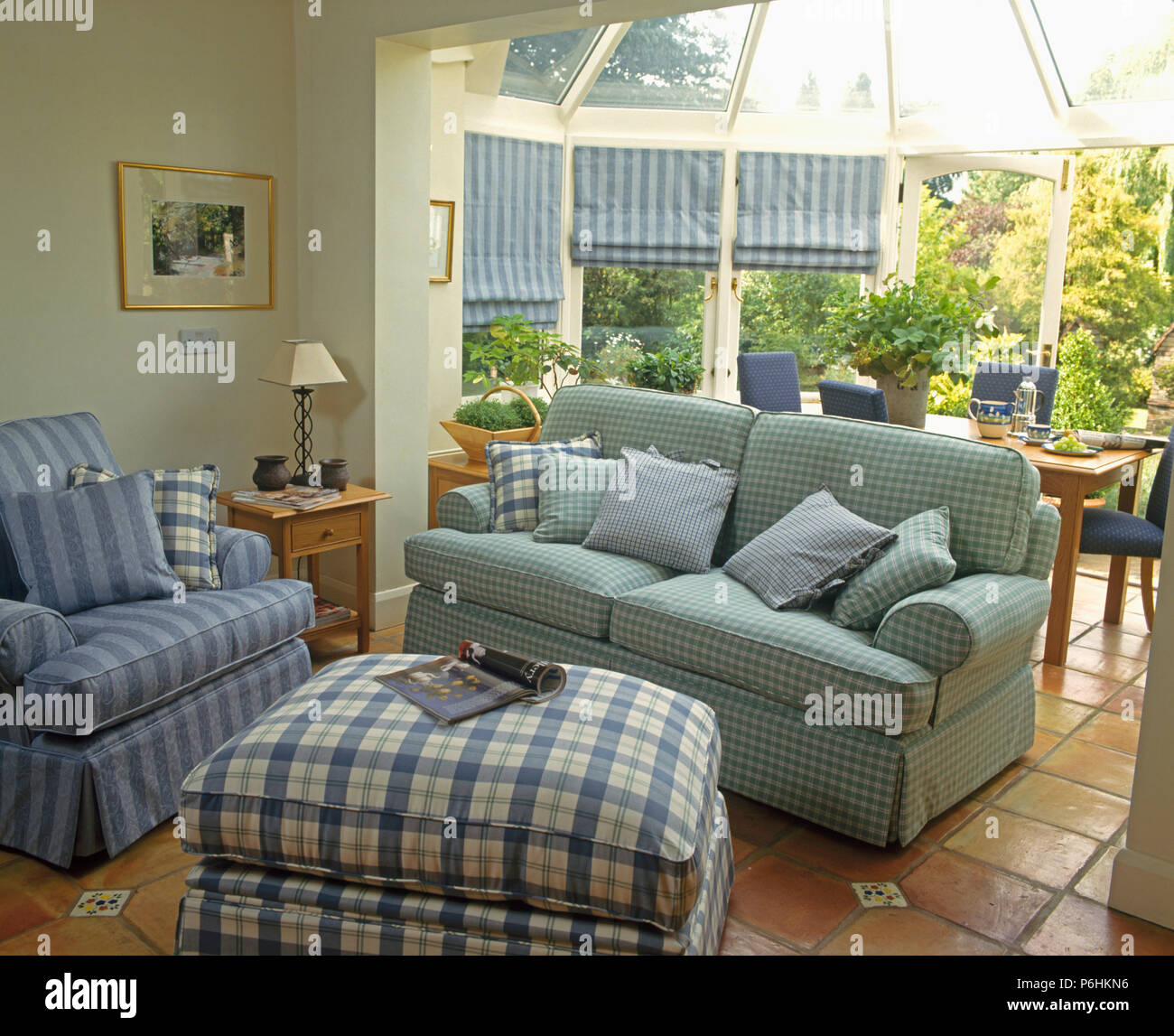 Checked ottoman with pale blue sofa and armchair in living room with dining room extension Stock