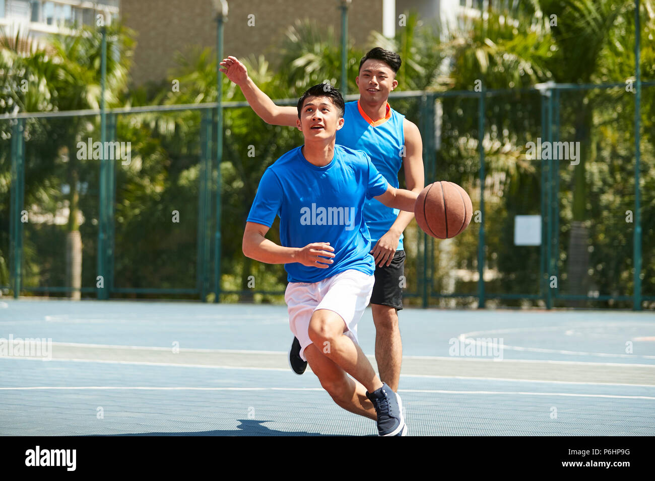 young asian male basketball player playing one-on-one on outdoor court. Stock Photo