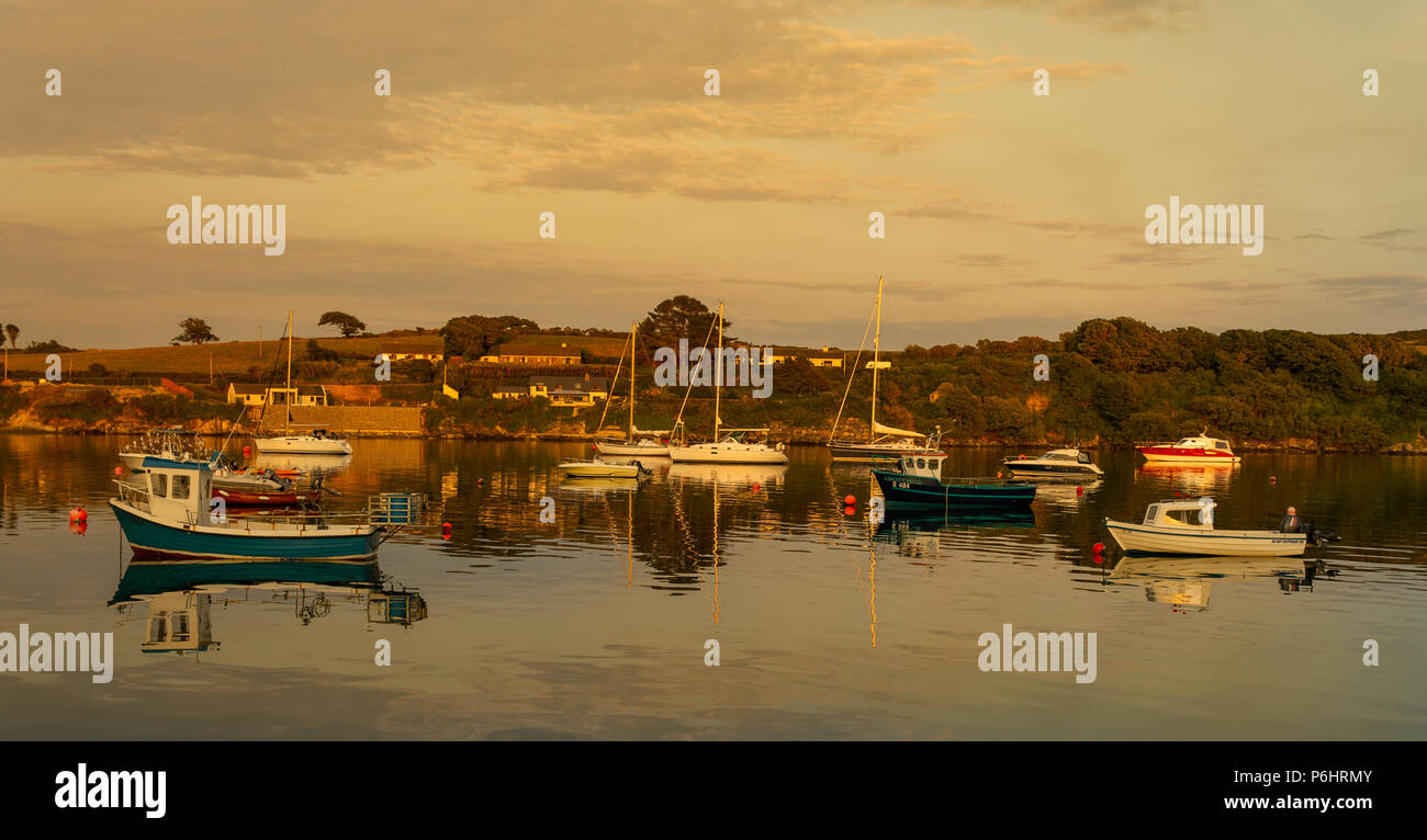 sunset on flat calm waters of castletownshend harbour, Ireland, with a mixture of boats at anchor. Stock Photo
