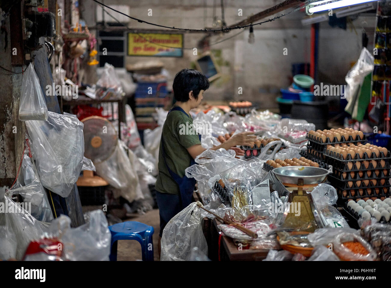 Thailand indoor market and female vendor surrounded by plastic bags ironically on International plastic bag free day 2018 Stock Photo