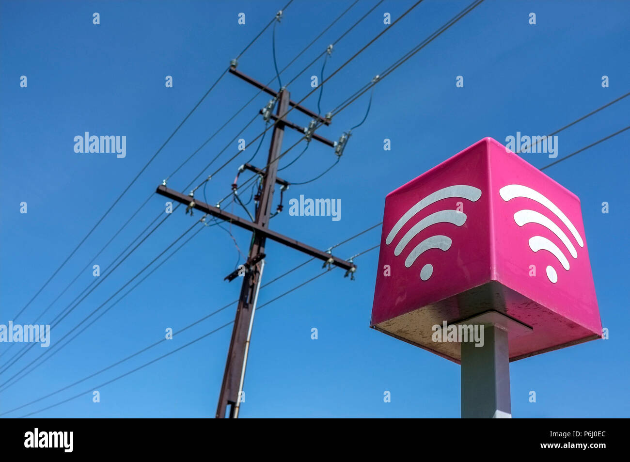 Telephone lines and Wi Fi sign against a blue sky. Stock Photo