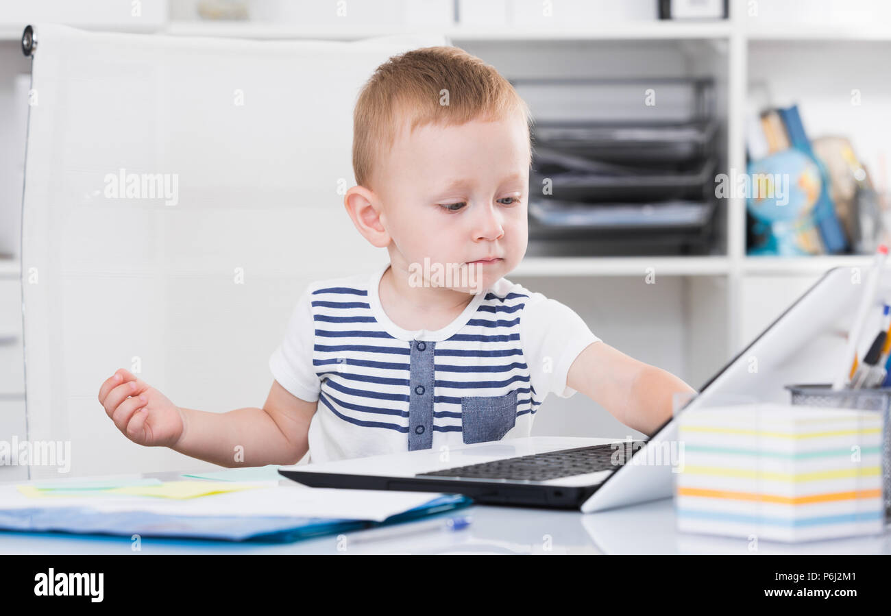 Kid is watching cartoons on laptop in the office. Stock Photo
