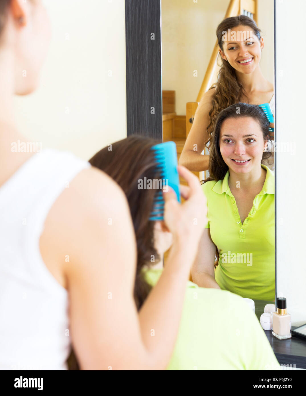 Happy girls combing the hair in front of mirror Stock Photo - Alamy