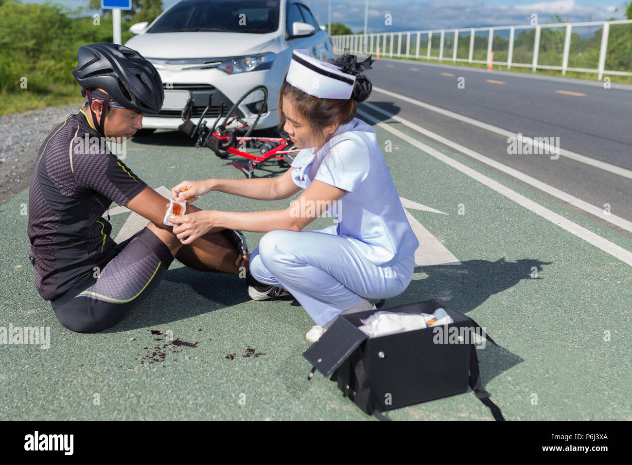 Female nurse helping emergency asia cyclist injured on the street bike ...