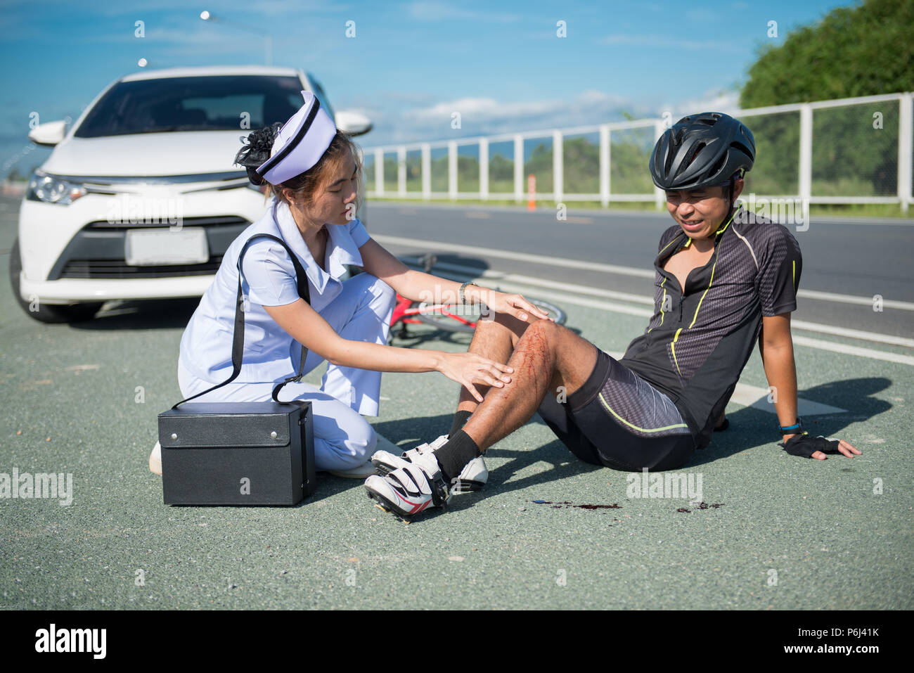 Female nurse helping emergency asia cyclist injured on the street bike ...