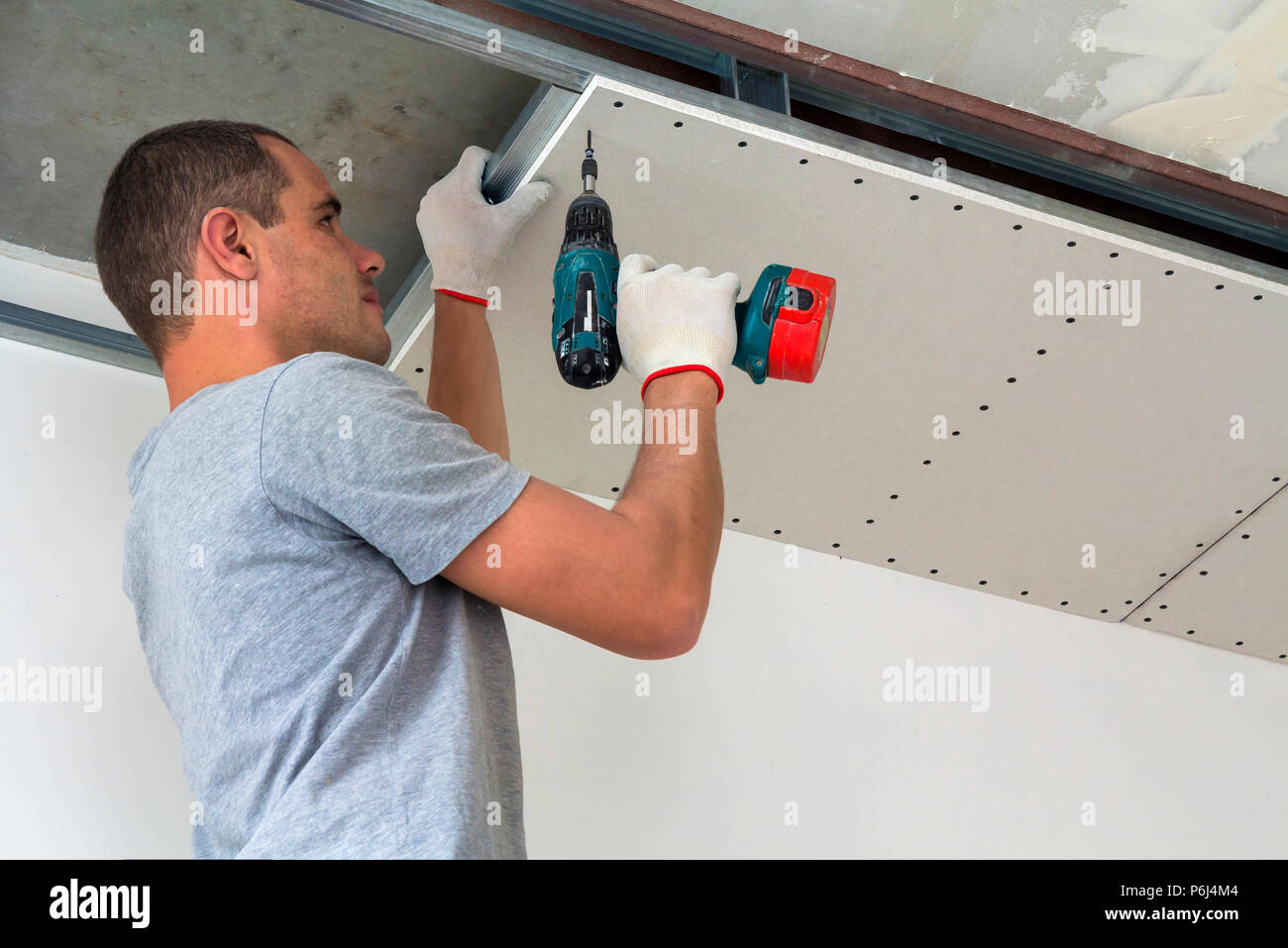 Construction Worker Assemble A Suspended Ceiling With Drywall And