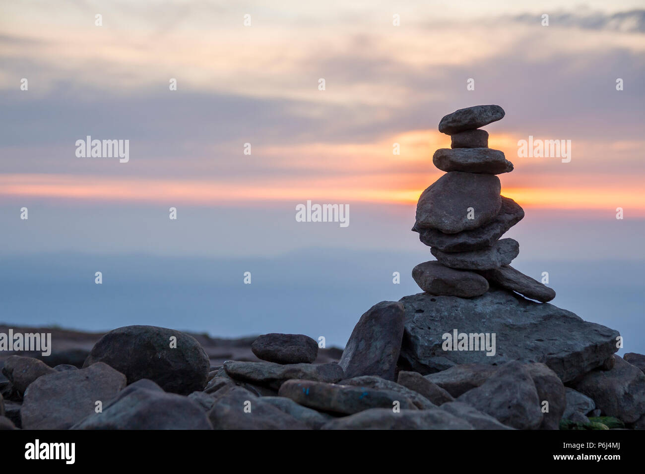 Close-up abstract image of rough natural brown uneven different sizes and forms mountain stones balanced like pyramid pile on bright light blue copy s Stock Photo