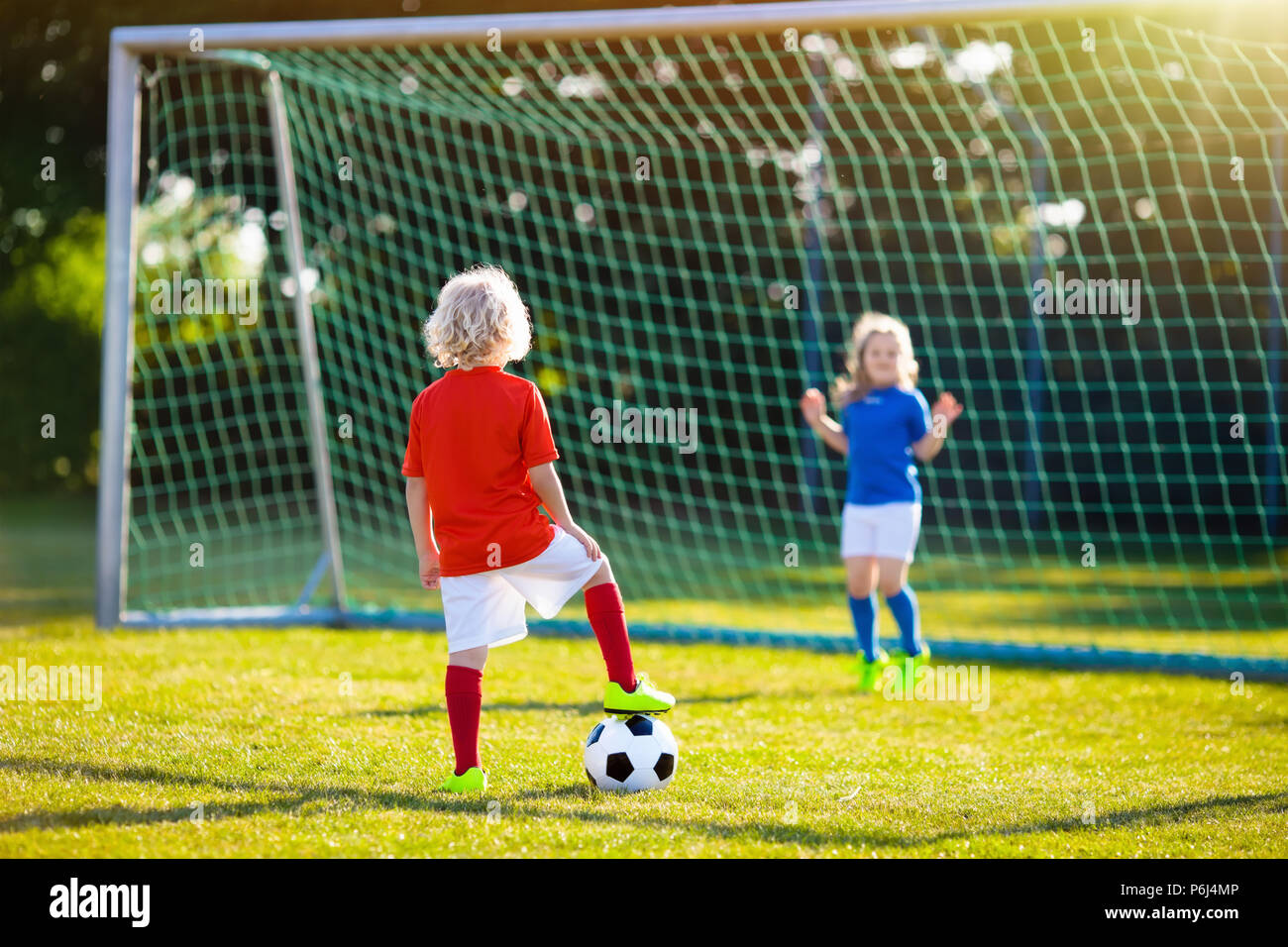 Kids play football on outdoor field. Children score a goal at soccer