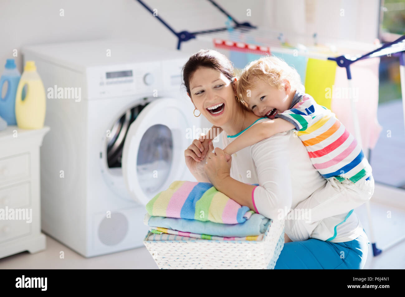 Mother and kids in laundry room with washing machine or tumble dryer. Family chores. Modern