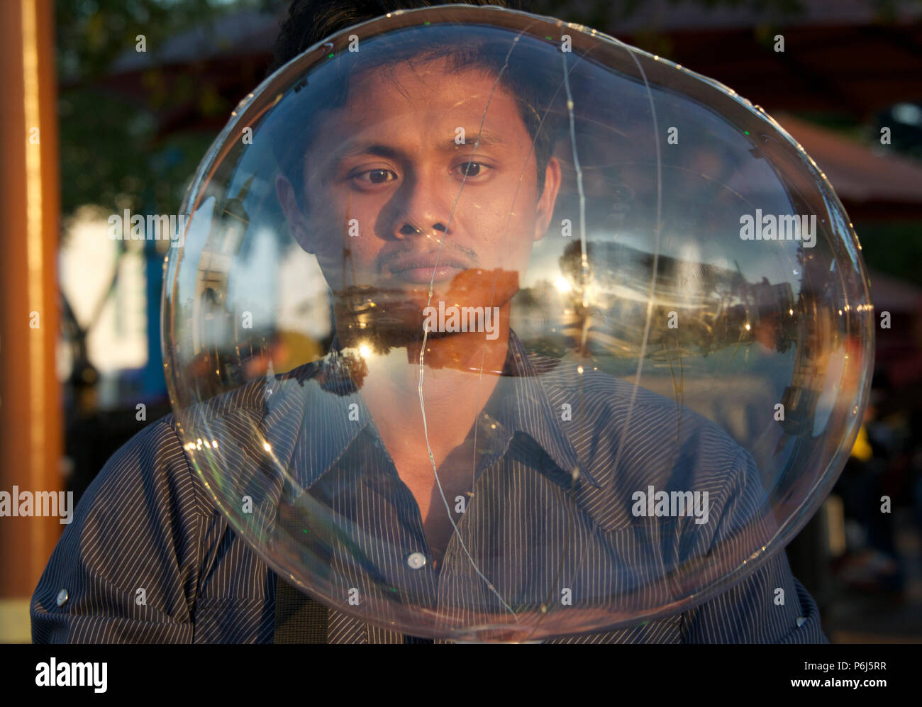 Portrait of a man viewed through giant soap bubble Waterfront promenade Kuching Sarawak Malaysia Stock Photo