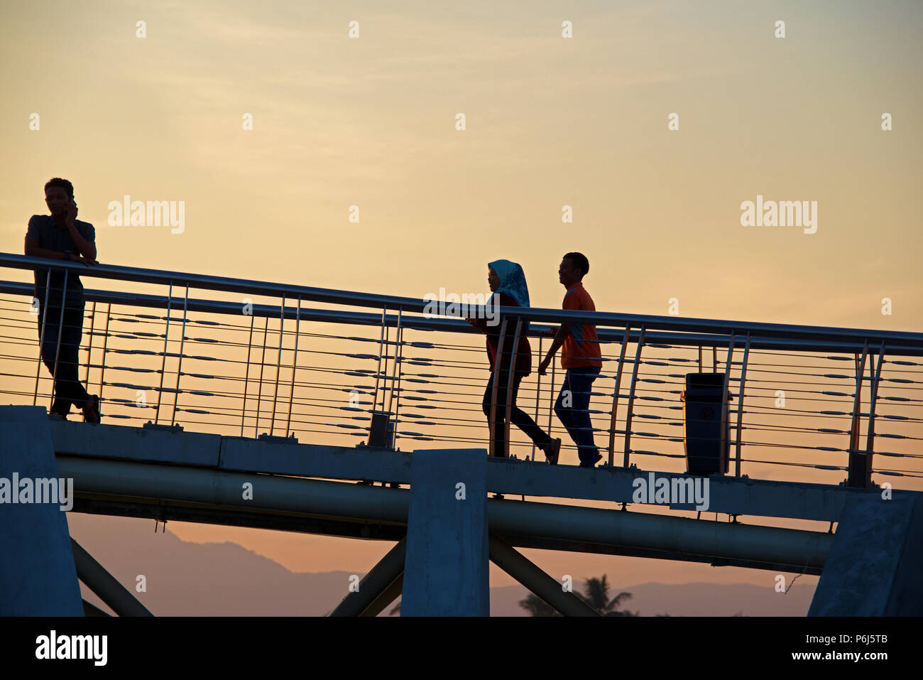 Silhouette people on Harmony aka Golden pedestrian footbridge spanning Kuching River Sarawak Malaysia Stock Photo