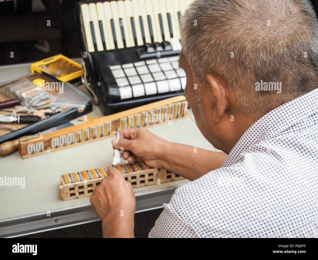Old man repairing the reed blocks of a vintage accordion, Beijing ...