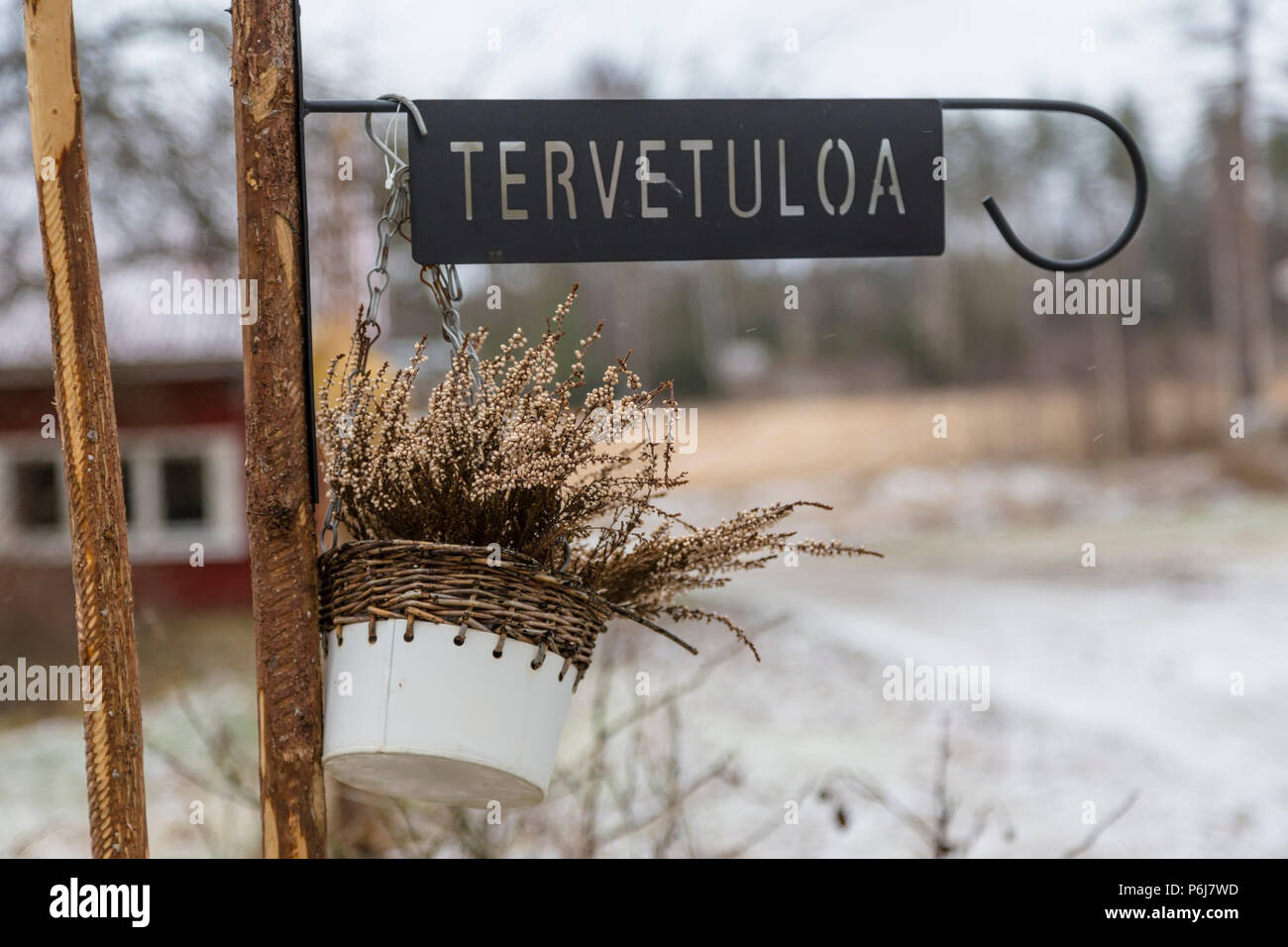 Forged metal plaque with the inscription - 'Welcome' in the Finnish language, and hanging on the fence potted plants Stock Photo