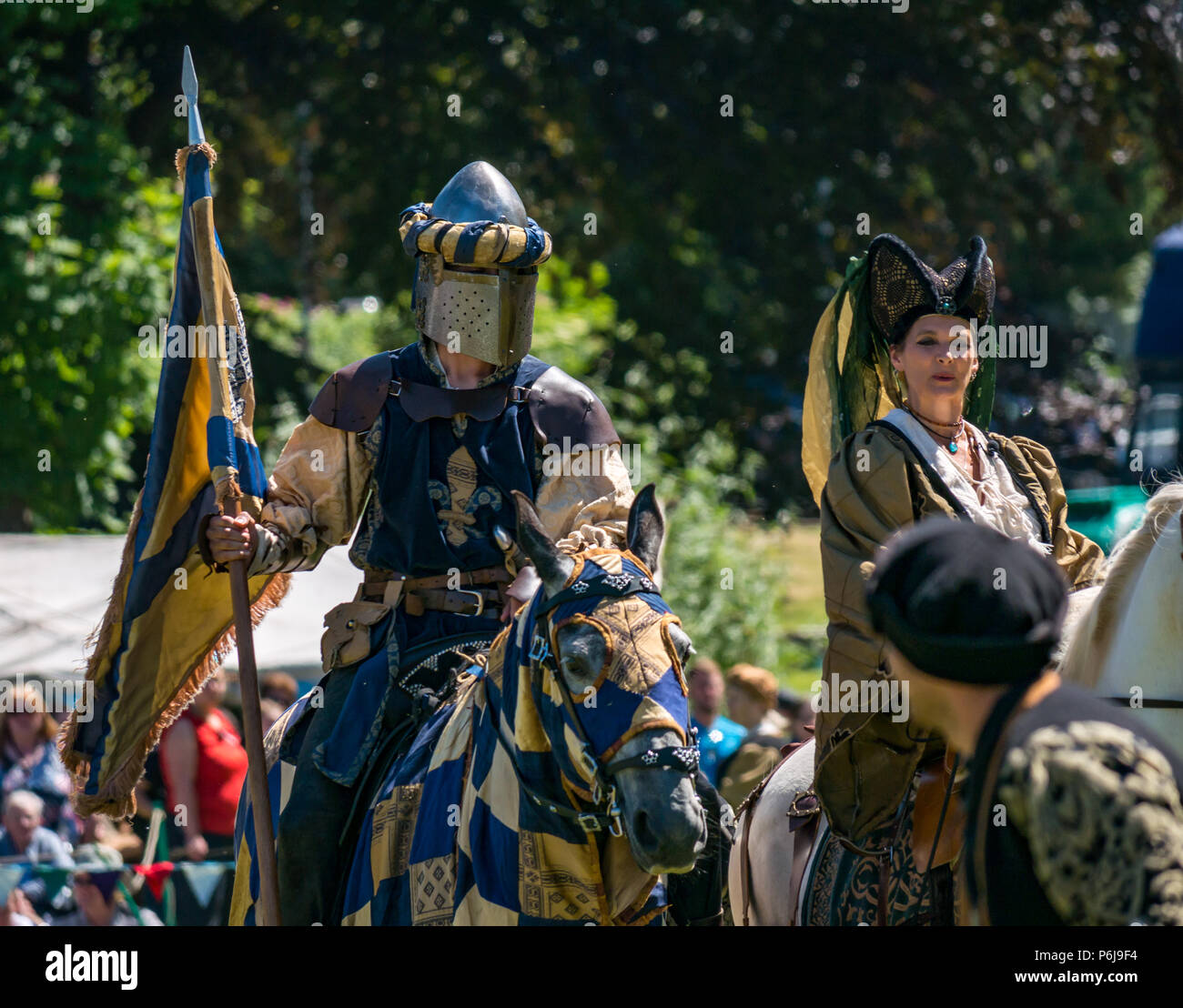 Jousting and Medieval Fair at Linlithgow Palace, Linlithgow, Scotland, United Kingdom, 30th June 2018. Historic Environment Scotland kick off their summer entertainment programme with a fabulous display of Medieval jousting in the grounds of the historic castle. The jousting is performed by Les Amis D'Onno equine stunt team. A knight wearing a helmet on a horse and a medieval lady on a white horse Stock Photo