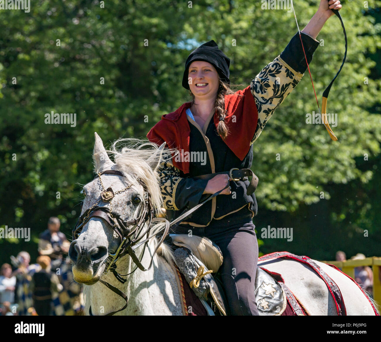 Jousting at Linlithgow Palace, Linlithgow, Scotland, United Kingdom, 30th June 2018. Historic Environment Scotland kick off a summer entertainment programme with a fabulous display of Medieval jousting in the Peel grounds of the historic castle. The jousting is performed by skilled horsemen of Les Amis D'Onno equine stunt team, based. Female horse rider performer cheers after her archery shot Stock Photo