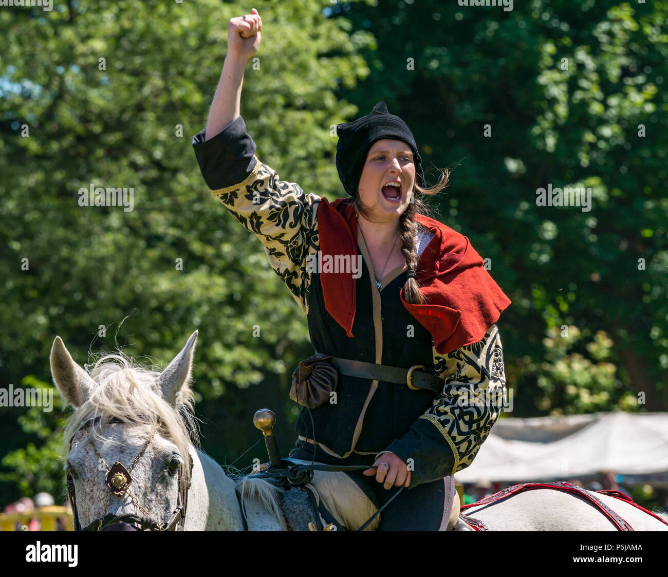 Jousting at Linlithgow Palace, Linlithgow, Scotland, United Kingdom, 30th June 2018. Historic Environment Scotland kick off a summer entertainment programme with a fabulous display of Medieval jousting in the Peel grounds of the historic castle. The jousting is performed by skilled horsemen of Les Amis D'Onno equine stunt team, based. Female horse rider performer cheers after her archery shot Stock Photo