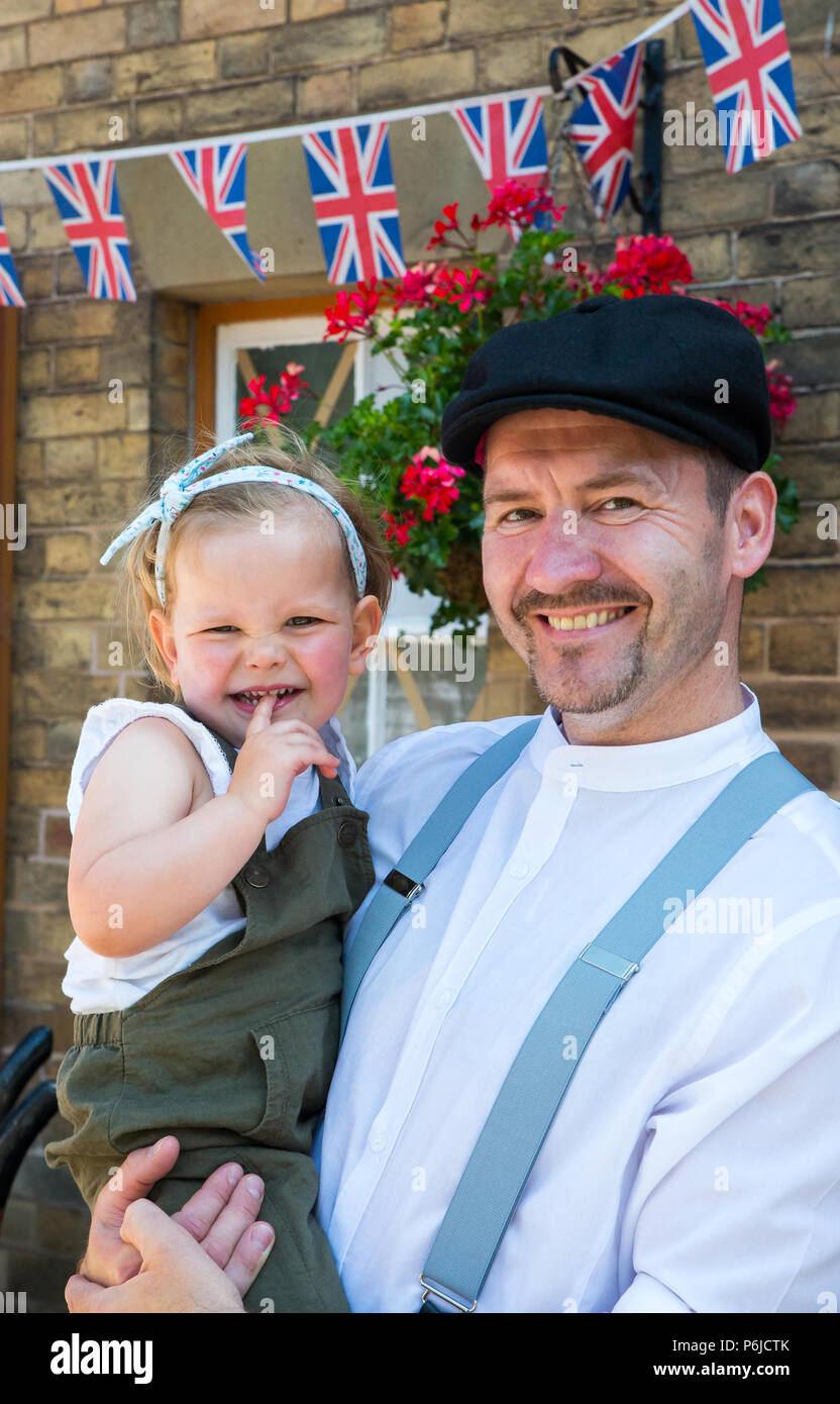 Kidderminster, UK. 30th June, 2018. A journey back in time begins on the Severn Valley Railway as we turn the clock back to the 1940s. Visitors and staff pull out all the stops to ensure a realistic wartime Britain is experienced on this heritage railway line. A happy father poses here at a vintage station for a portrait photograph with his cute little baby girl in his arms - both dressed in 1940s costume. Credit: Lee Hudson/Alamy Live News Stock Photo