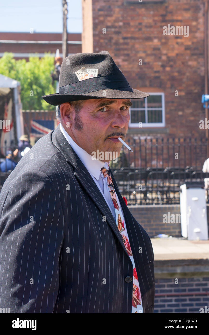 Kidderminster, UK. 30th June, 2018. A journey back in time continues at the Severn Valley Railway as we turn the clock back to the 1940s. Visitors and staff ensure a realistic second world war Britain is experienced on this heritage railway line. A dodgy 1940s, WW2 spiv, in black trilby hat, on the vintage platform at Kidderminster SVR station tries to tempt passengers with his black market goods! Credit: Lee Hudson/Alamy Live News Stock Photo