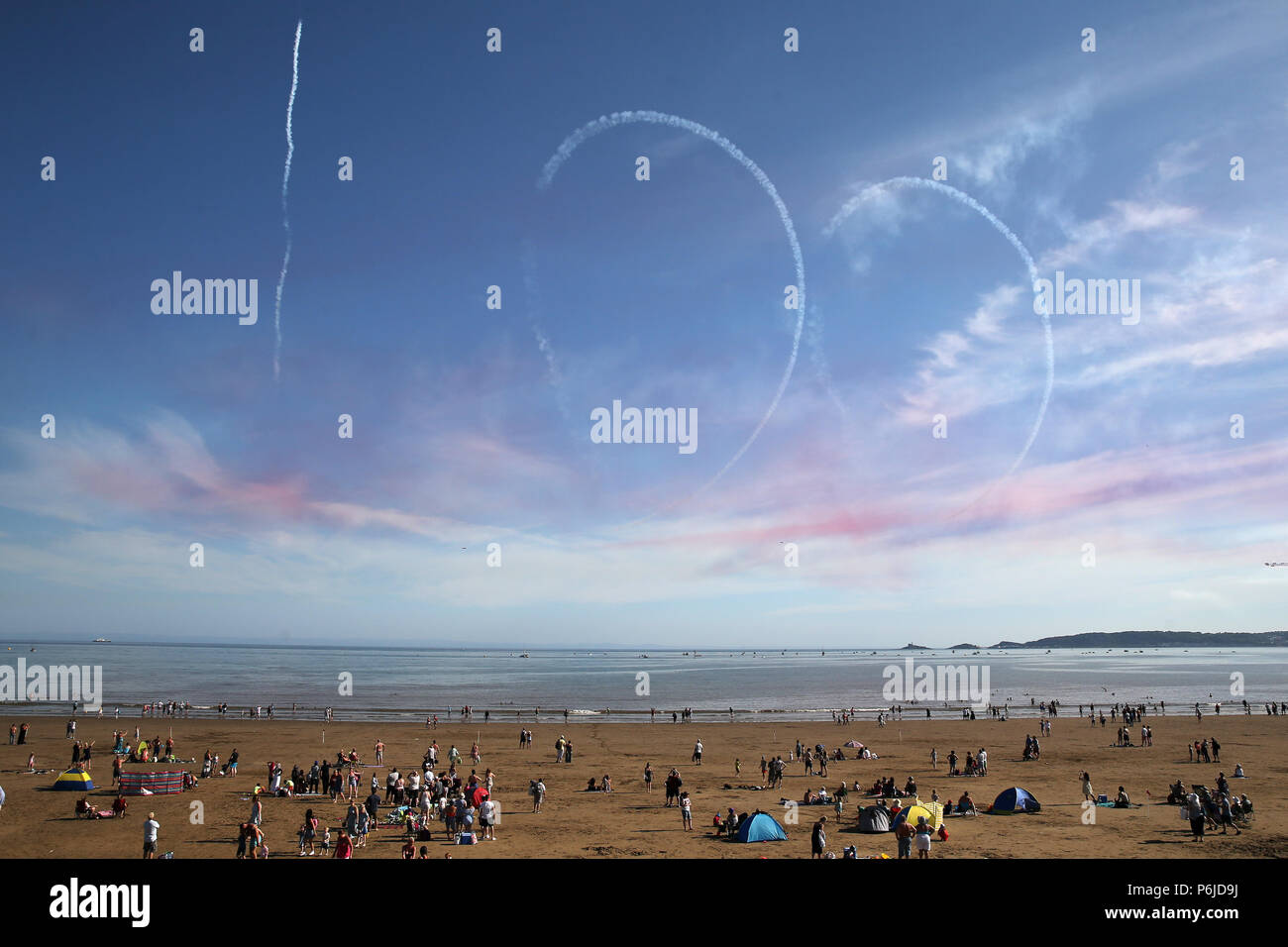 Swansea, UK. 30th Jun, 2018. Crowds on the beach look on as a 100 smoke trail is left by the Red Arrows to commemorate the centenary of the RAF .The RAF Red Arrows performing at The Wales Airshow 2018 in Swansea Bay, South Wales on Saturday 30th June 2018. pic by Andrew Orchard/Alamy Live News Stock Photo