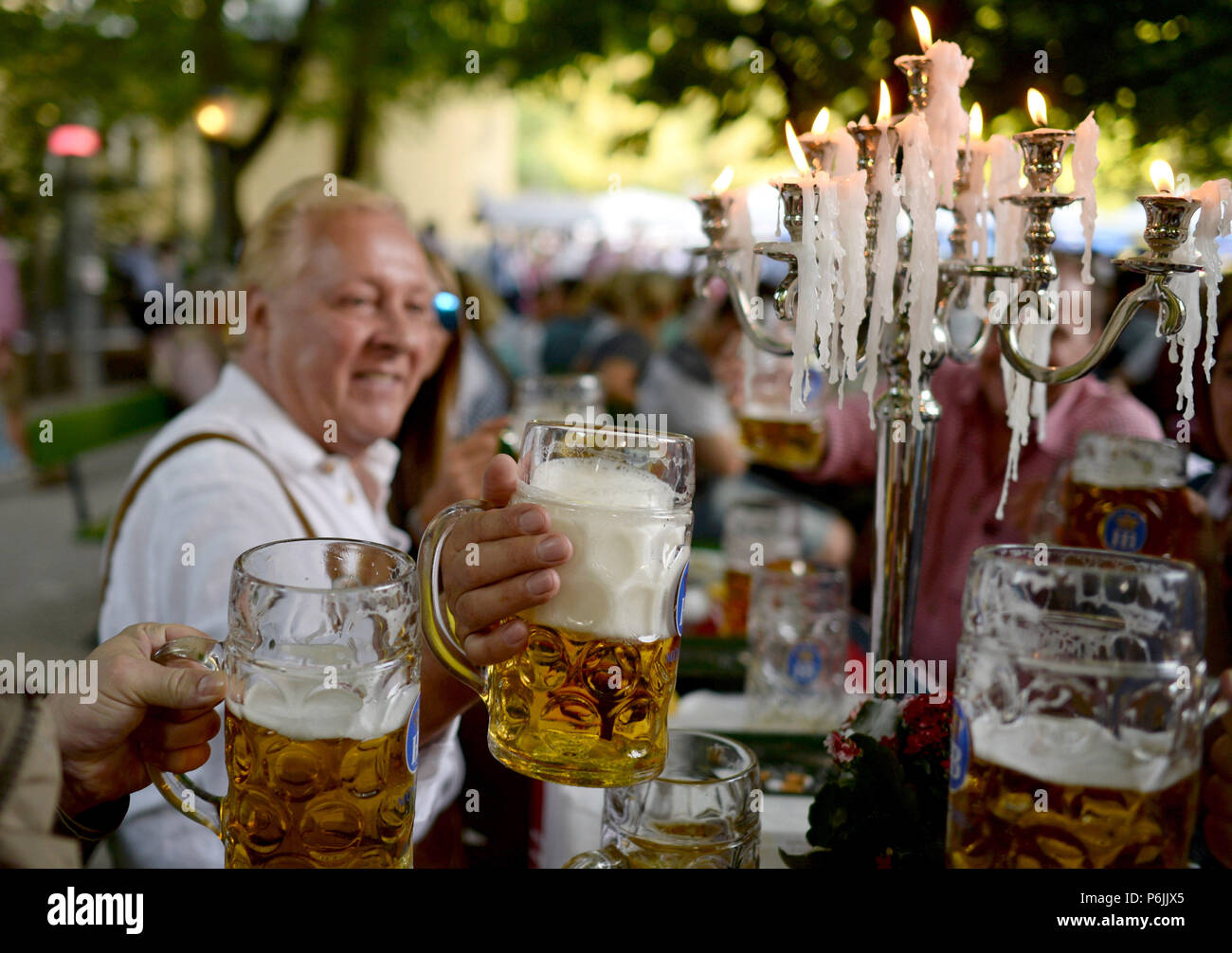 Munich, Germany. 19th July, 2015. A group of men sitting in the beergarden at the Chinese Tower in the English garden and during the traditional Kocherlball toast with beer. Once a year, the British magazine 'Monocle' compiles a ranking of the 25 'most liveable cities'. In 2018 the German metropolis Muenchen is once more among the top cities. Credit: Andreas Gebert/dpa/Alamy Live News Stock Photo