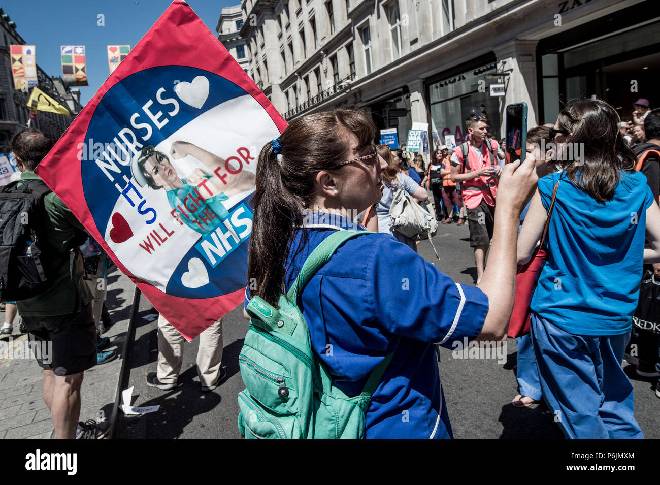A woman with a poster of nurses of the NHS. Tens of thousands of people marched during the hot Saturday weather through London to celebrate and demonstrate over Britain's National Health Service (NHS), ahead of its 70th birthday next week. Stock Photo