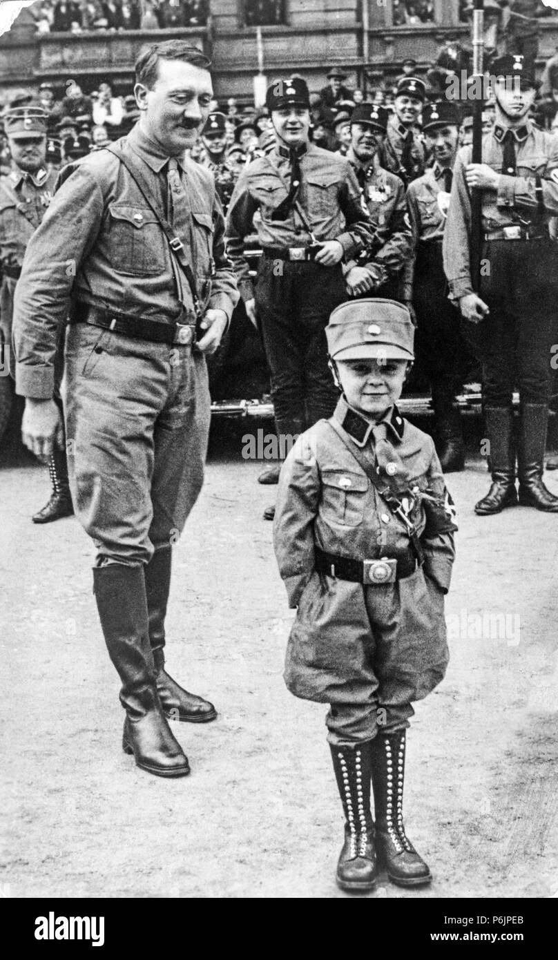 Adolf Hitler smiles at a young boy dressed in Nazi uniform during rally for the Nazi Party. Stock Photo