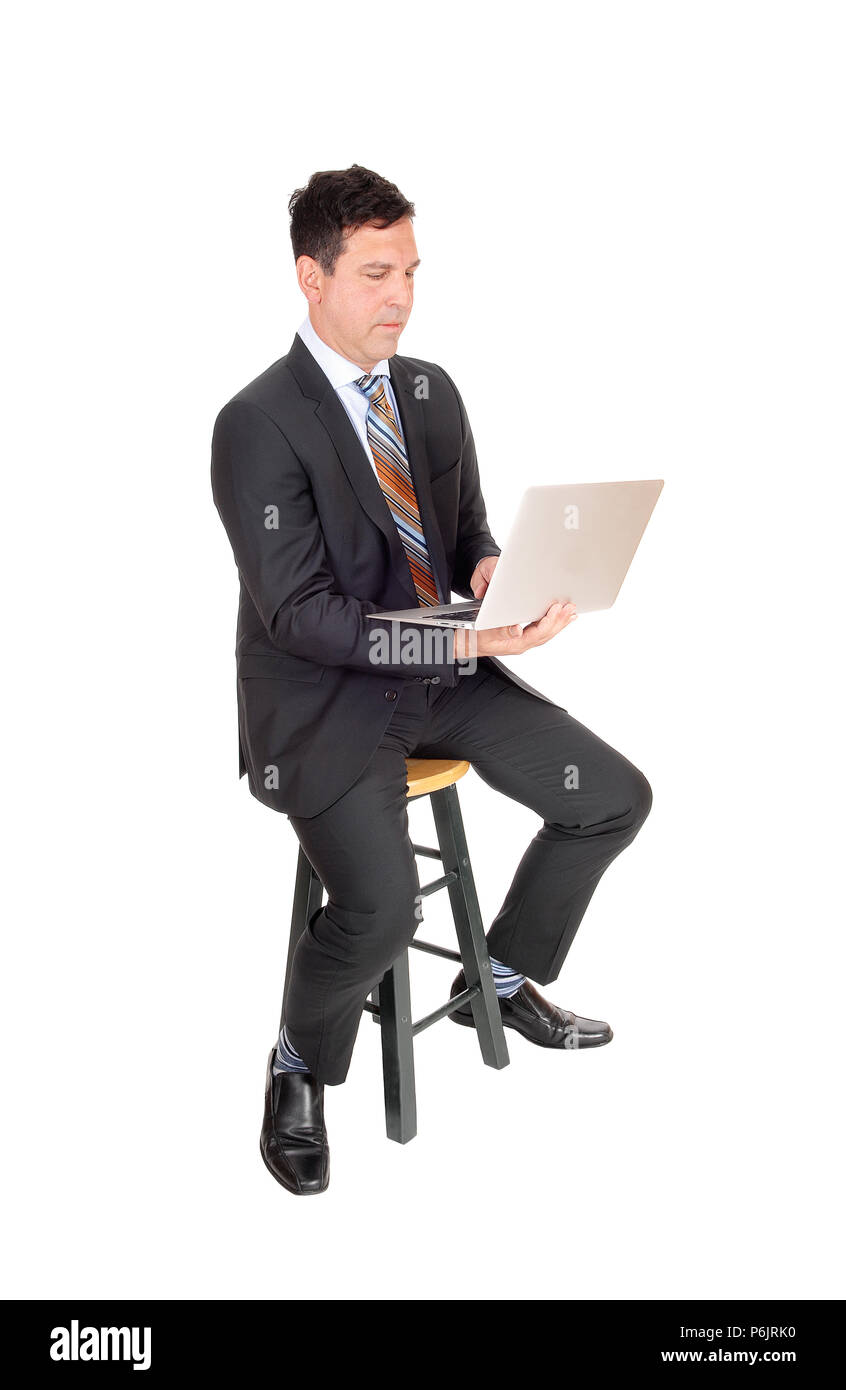 A handsome middle age business man sitting and working with his laptop, looking serious, isolated for white background Stock Photo