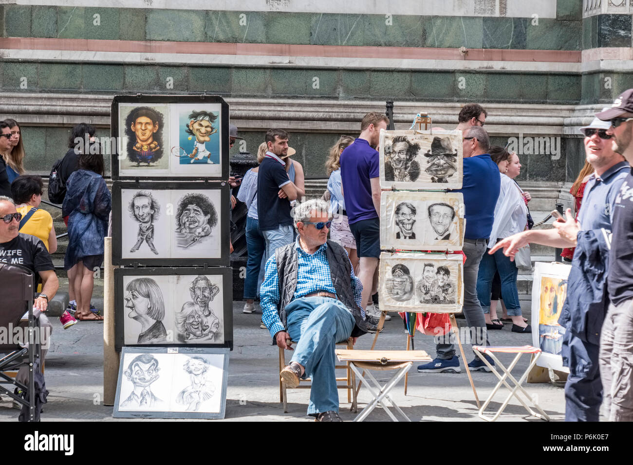 Florence, Italy. June 1, 2018: Cartoonist sitting waiting for customers in the Piazza del Duomo, behind, tourists and part of the wall of the Cathedra Stock Photo