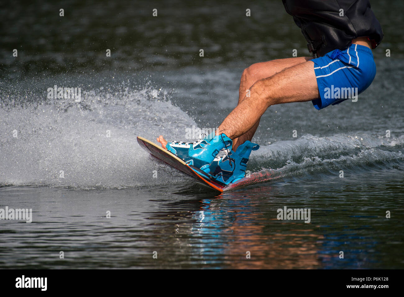 male wakeboarder rides on lake in wakeboard splashes of water Stock