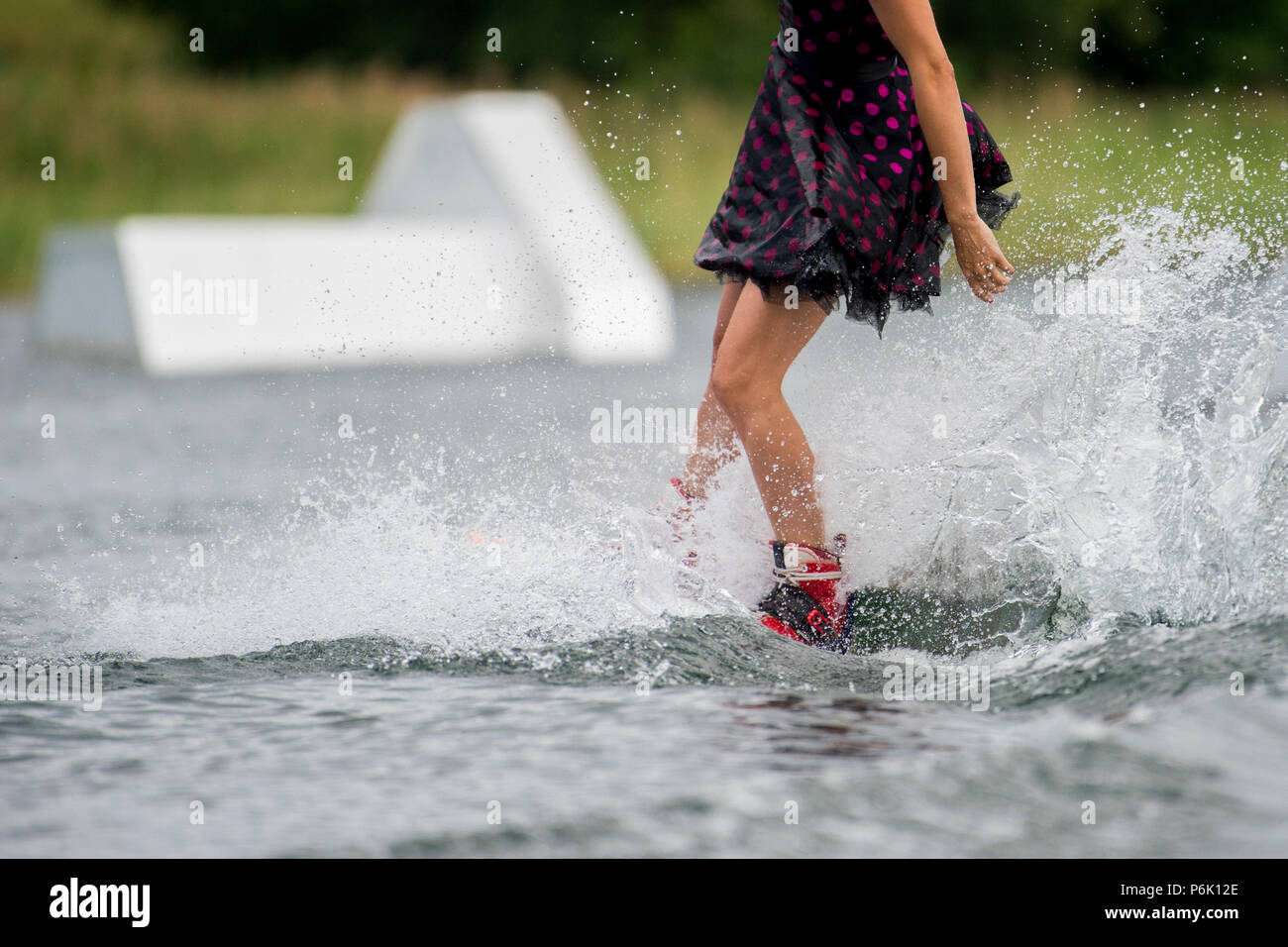 Woman in a skirt on a water ski is engaged in extreme sports. Wakeboard sport and girl. Stock Photo