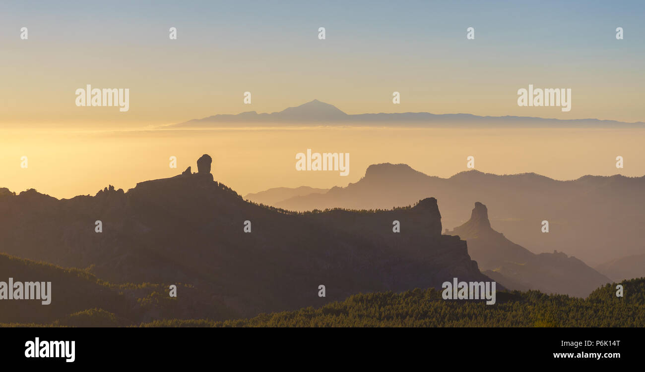 Silhouettes of Roque Nublo and Bentayga against sunset light. Pico de Teide on background. Gran Canaria, Canary islands, Spain Stock Photo