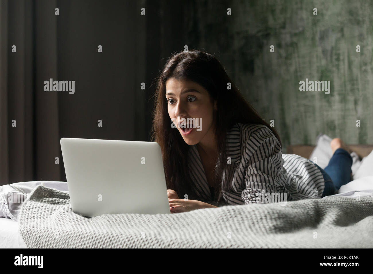 Surprised girl shocked receiving unexpected message at laptop Stock Photo