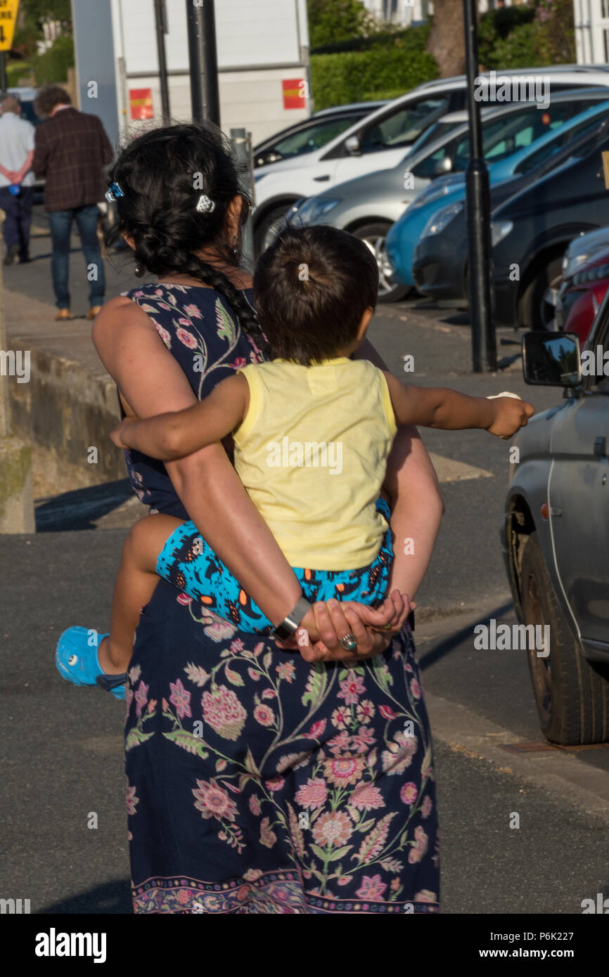 woman carrying baby on her back, piggy back. Stock Photo