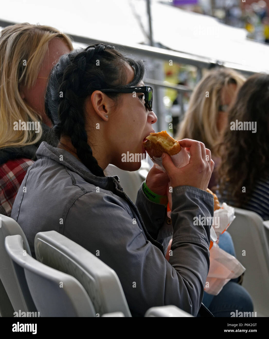 Woman spectator sitting in grandstand eating a pasty. Royal Highland Show 2018, Ingliston, Edinburgh, Scotland, United Kingdom, Europe. Stock Photo