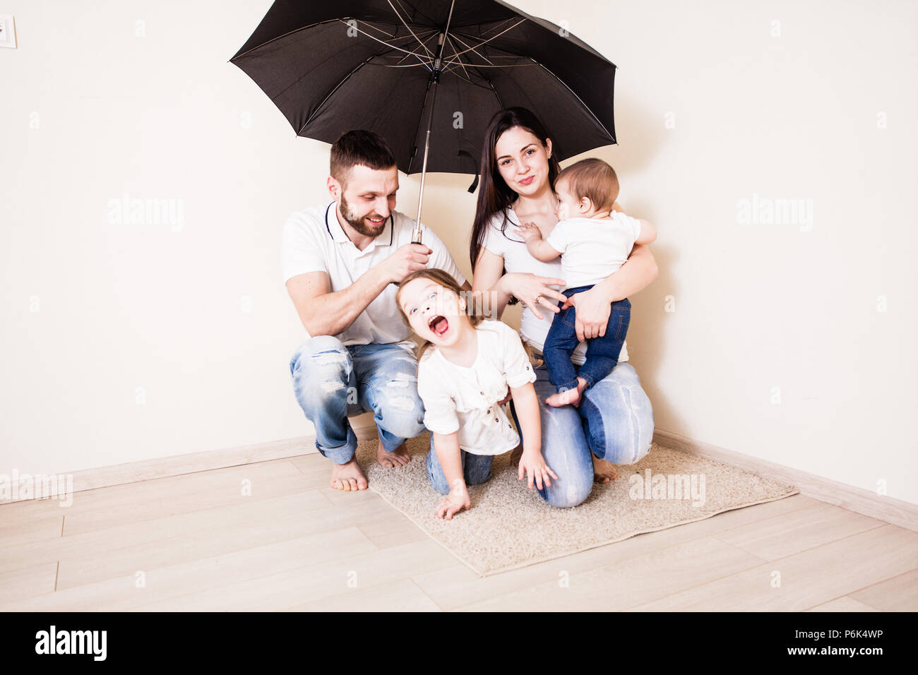 Family feeling safe sitting under umbrella Stock Photo Alamy