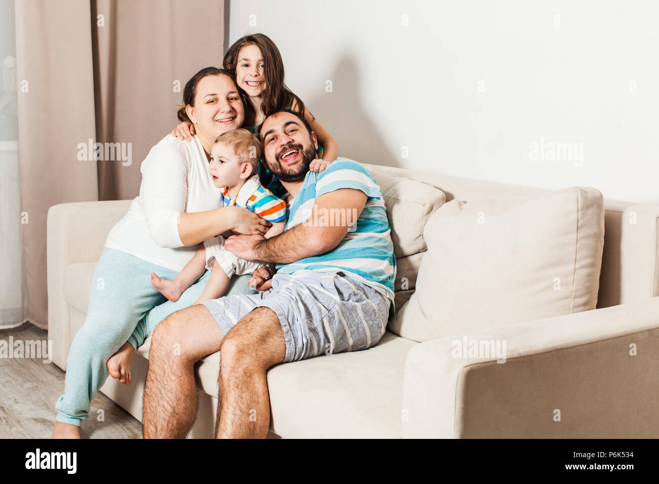 Beautiful family sitting on a couch in the living room Stock Photo - Alamy