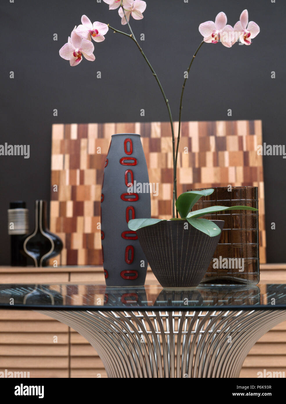 Closeup of pink orchid in pot on glass and metal table with modern