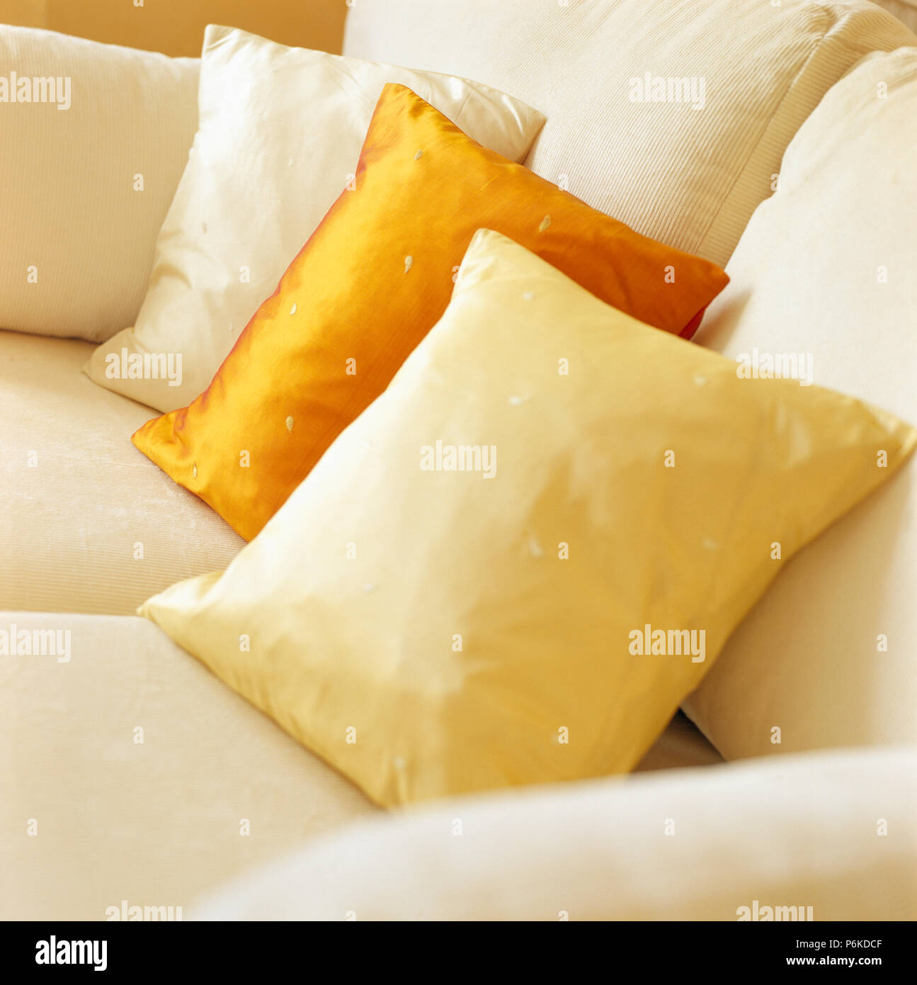 Close up of orange and pale yellow silk cushions on cream sofa