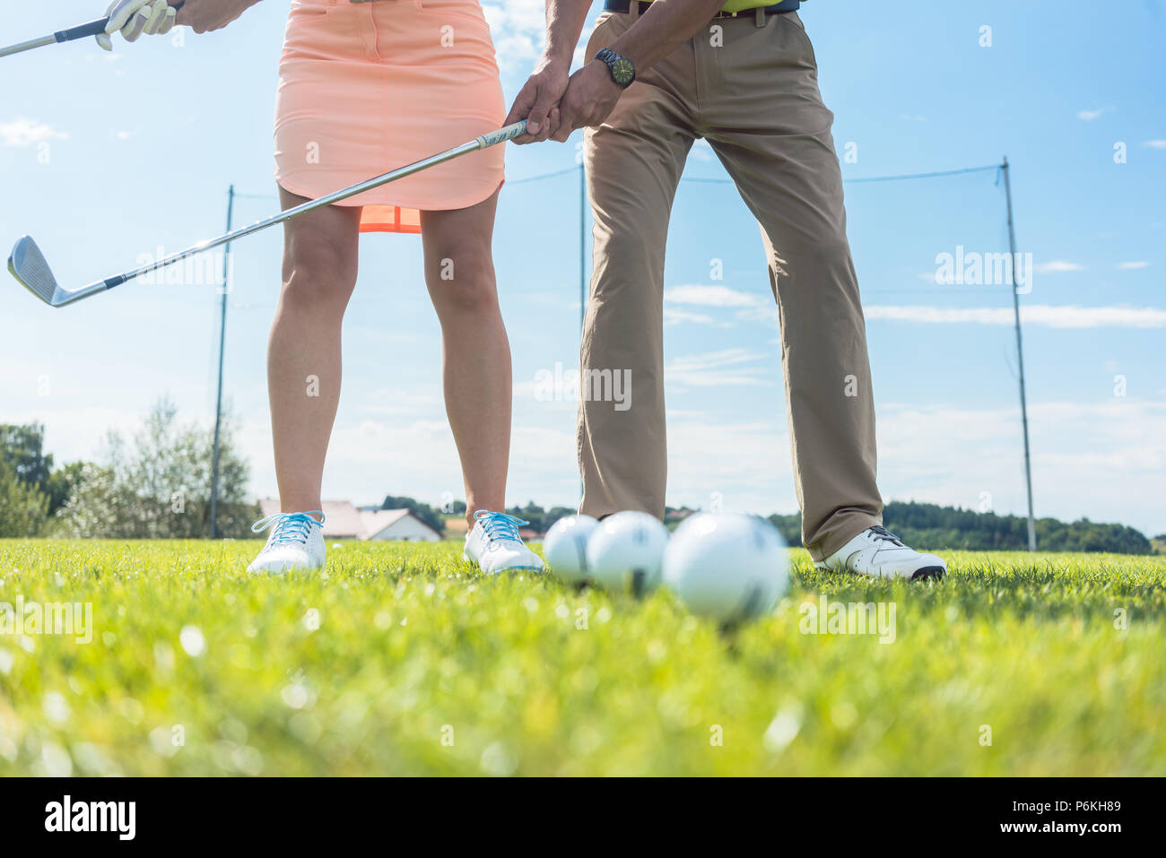 Low section of man and woman holding iron clubs while practicing Stock Photo