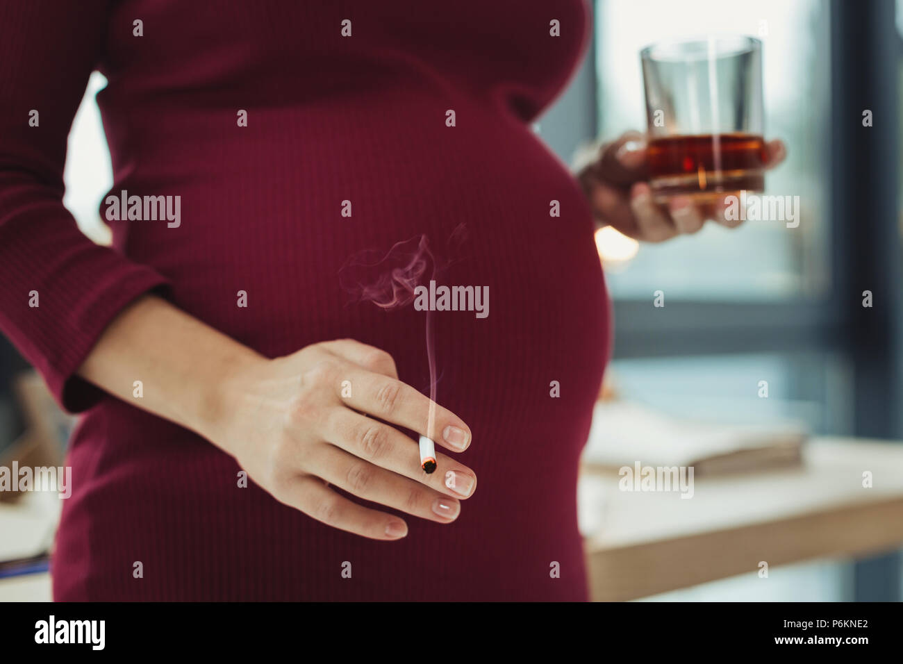 Irresponsible pregnant woman smoking and drinking alcohol Stock Photo