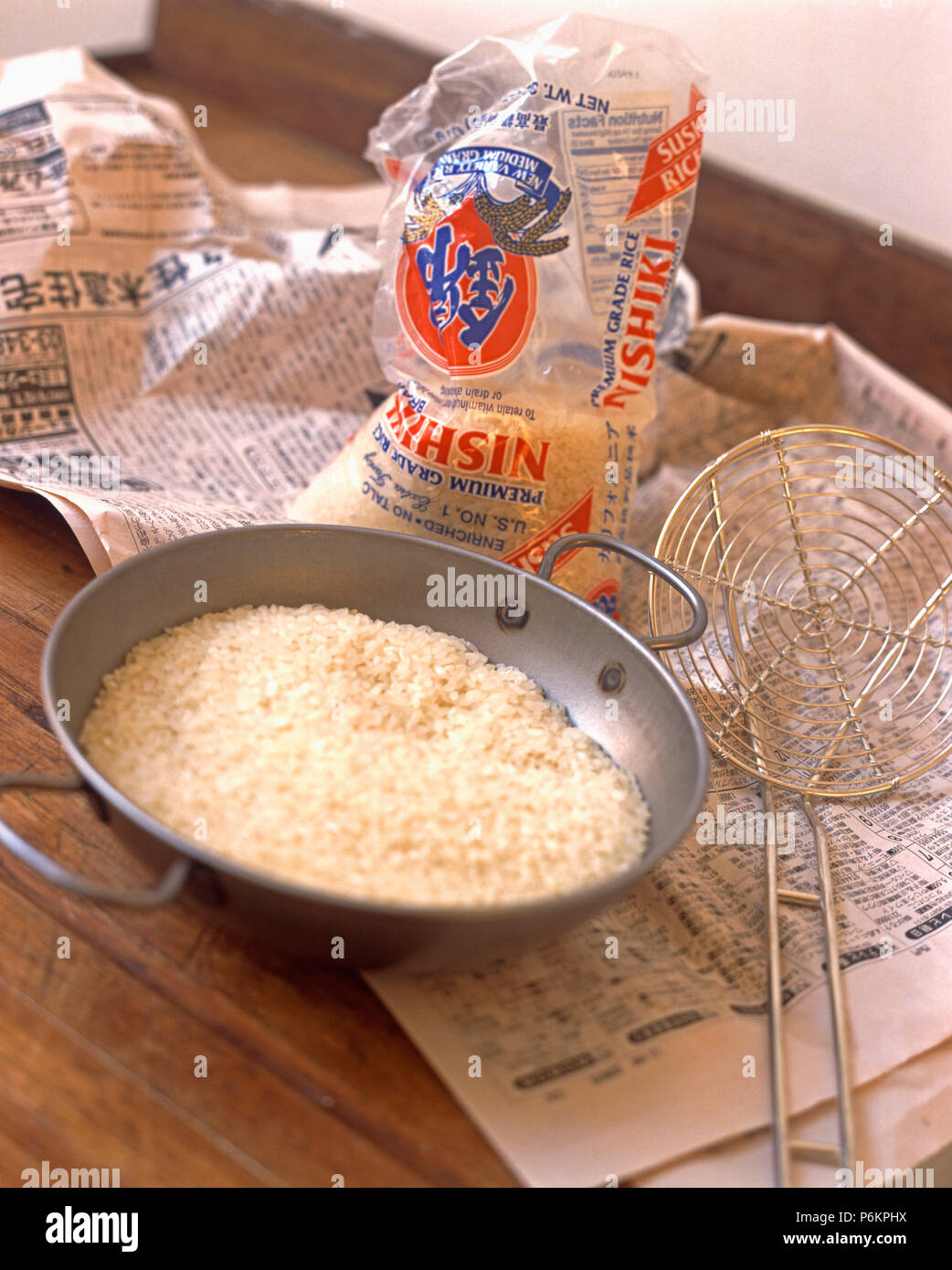 Closeup of rice in colander on table with packet of Chinese rice Stock