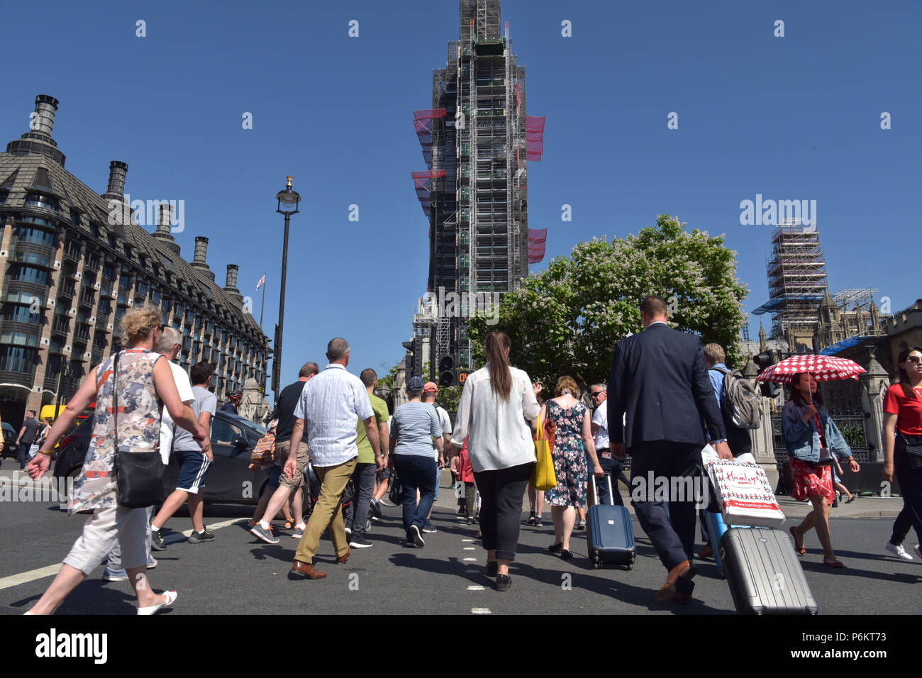 Tourists, visitors and office workers across the road in Westminster outside the Houses of Parliament where Big Ben is covered in scaffold as it under Stock Photo