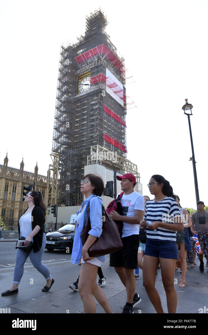 Tourists and visitors to London in Westminster outside the Houses of Parliament where Big Ben is covered in scaffold as it undergoes restoration. Stock Photo