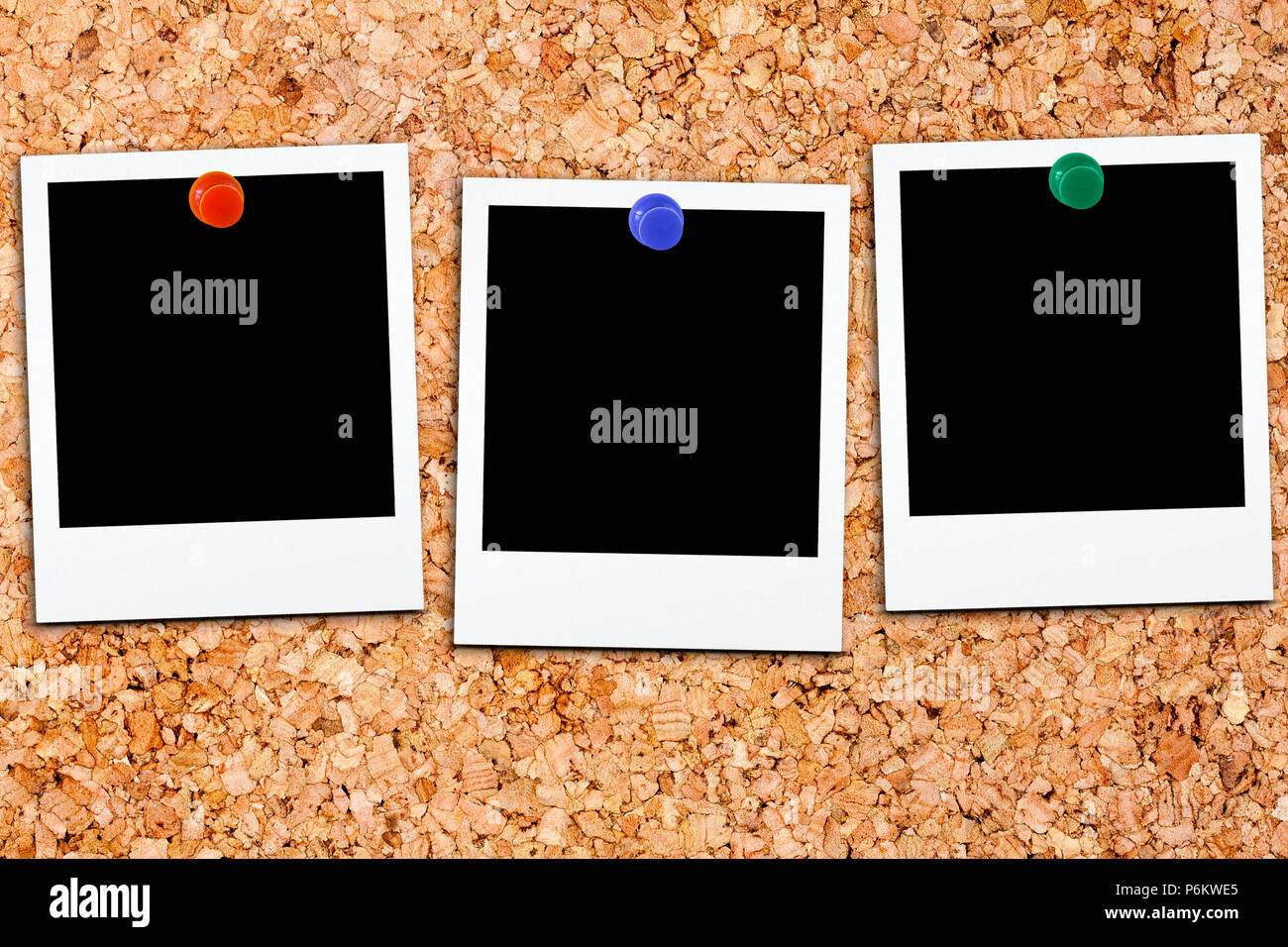 Three blank polaroids affixed on cork board with colorful small thumb tack Stock Photo