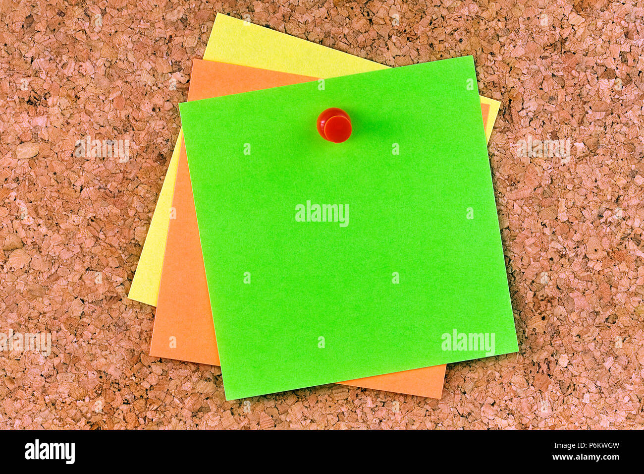 Stacked square blank postits affixed on cork board with red pushpin Stock Photo