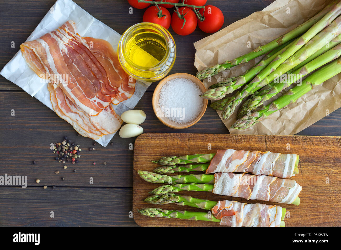 Fresh organic asparagus wrapped in Parma ham on a cutting board Stock