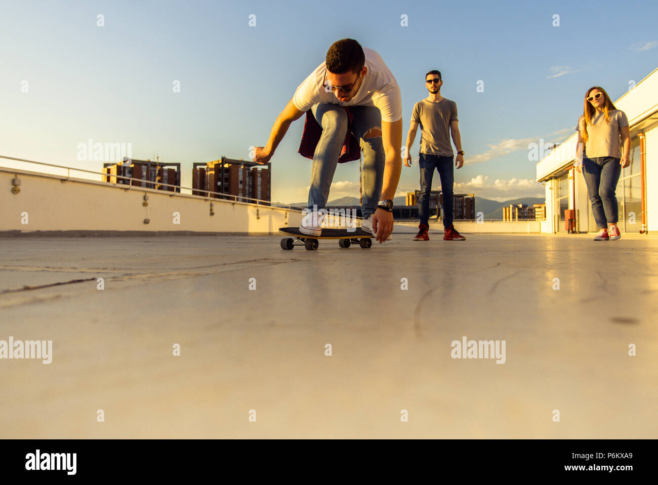 Friends having fun with skateboard on rooftop of the building Stock Photo -  Alamy