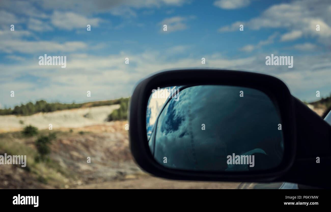 Reflections of old man in the mirror in the car close-up in Zaranda mines with blue sky with clouds, Spain Stock Photo