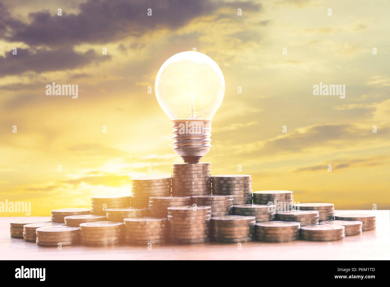 Energy saving light bulb and tree growing on stacks of coins on nature ...