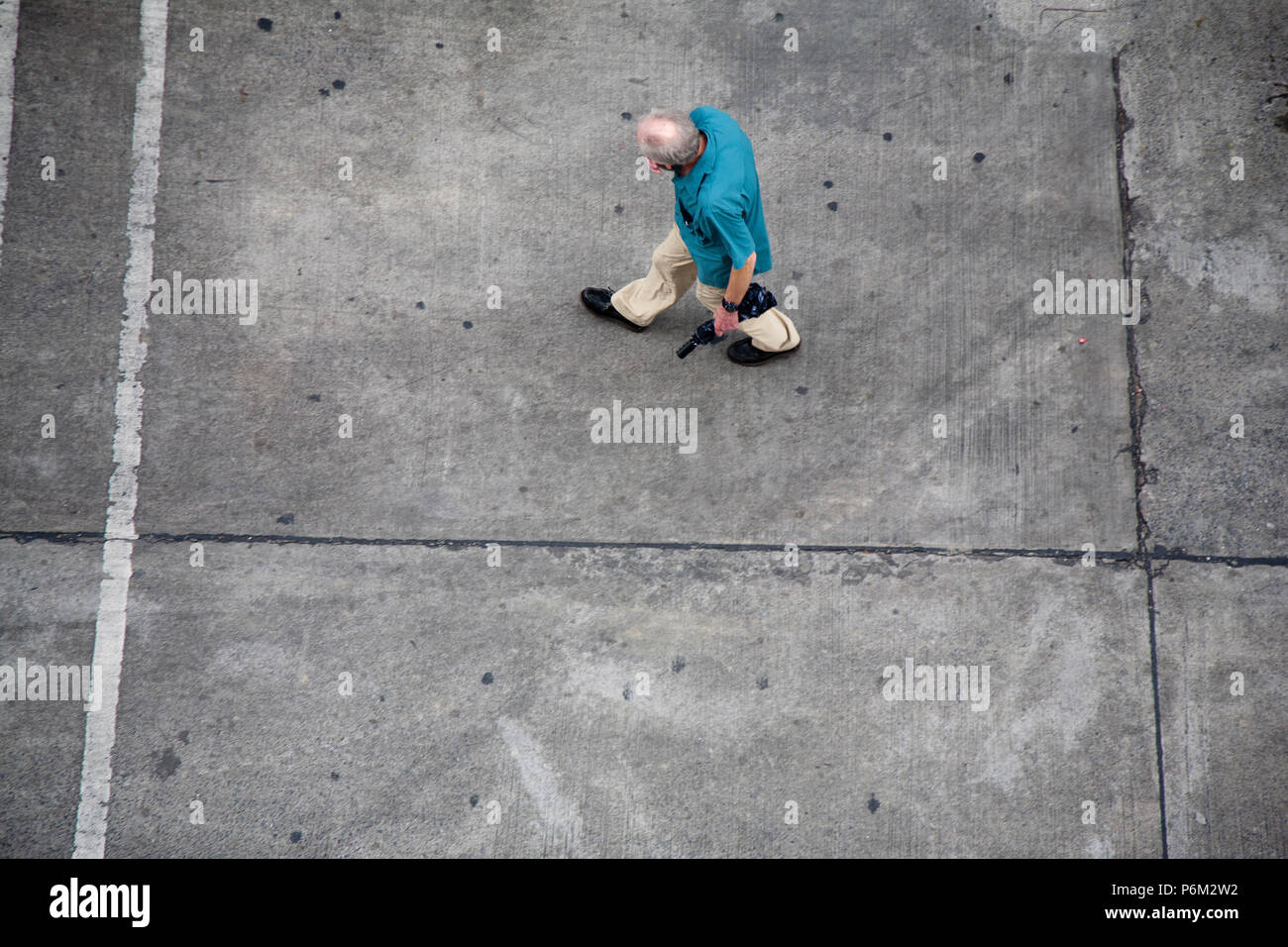 old retired tired person walking up a concrete road, alone, sad, needy Stock Photo